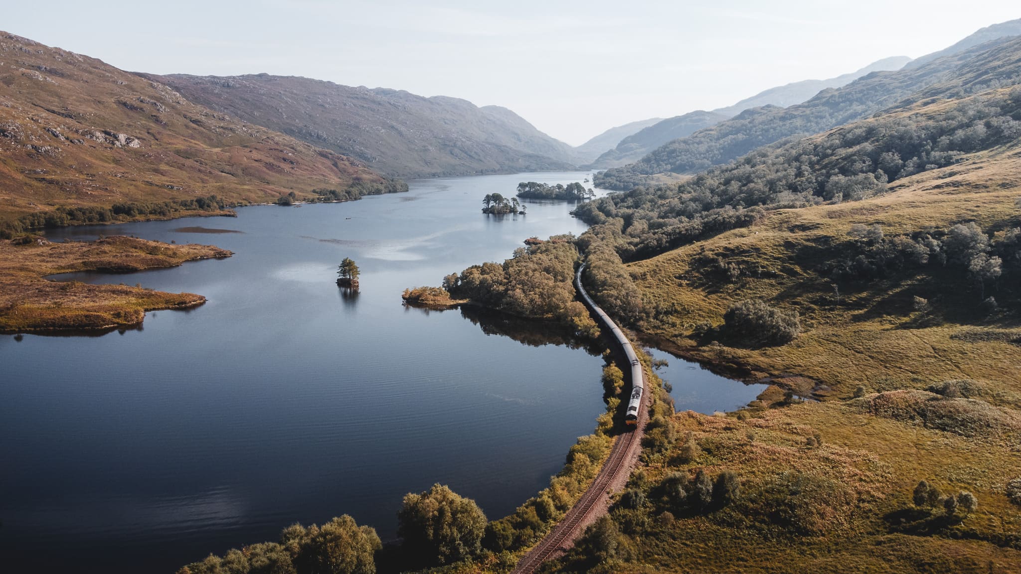 Jacobite Steam Train circulant entre un loch et les montagnes des Highlands