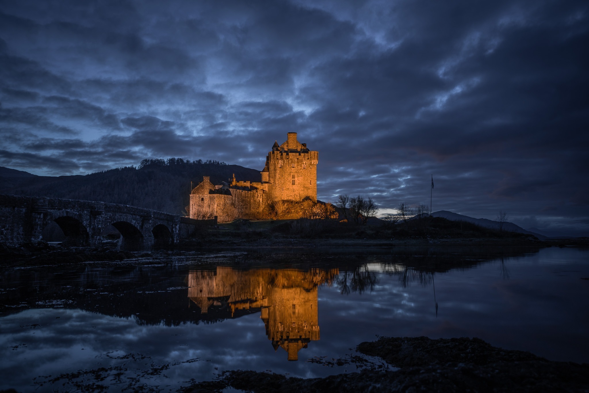 Eilean Donan Castle illuminé et reflété dans le loch à la tombée de la nuit